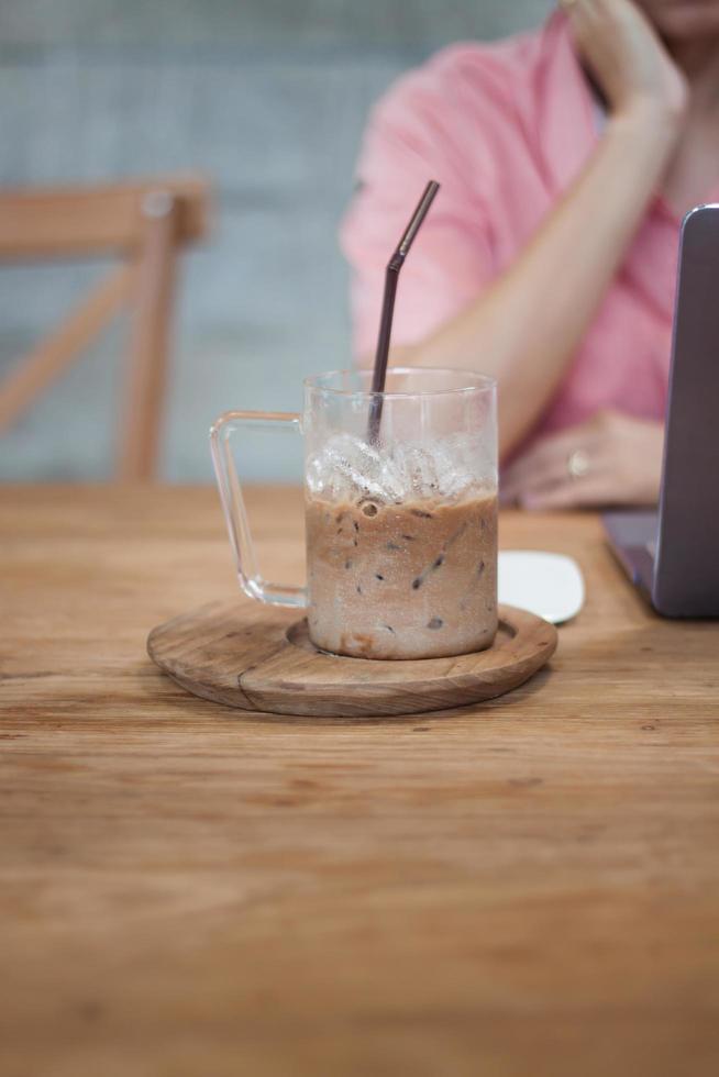 Iced coffee on a table with a woman working photo