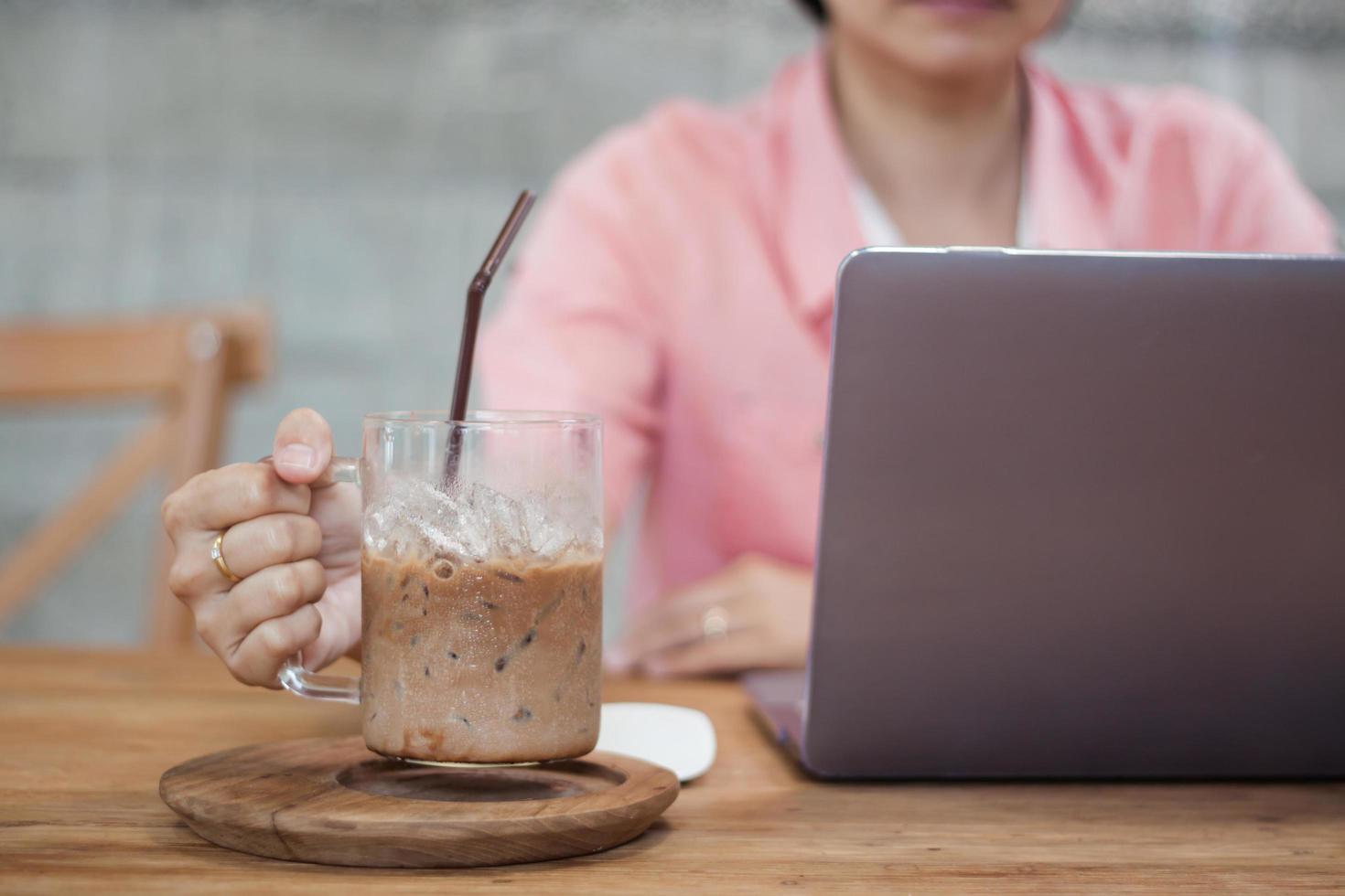 Woman holding a coffee while working on a computer photo