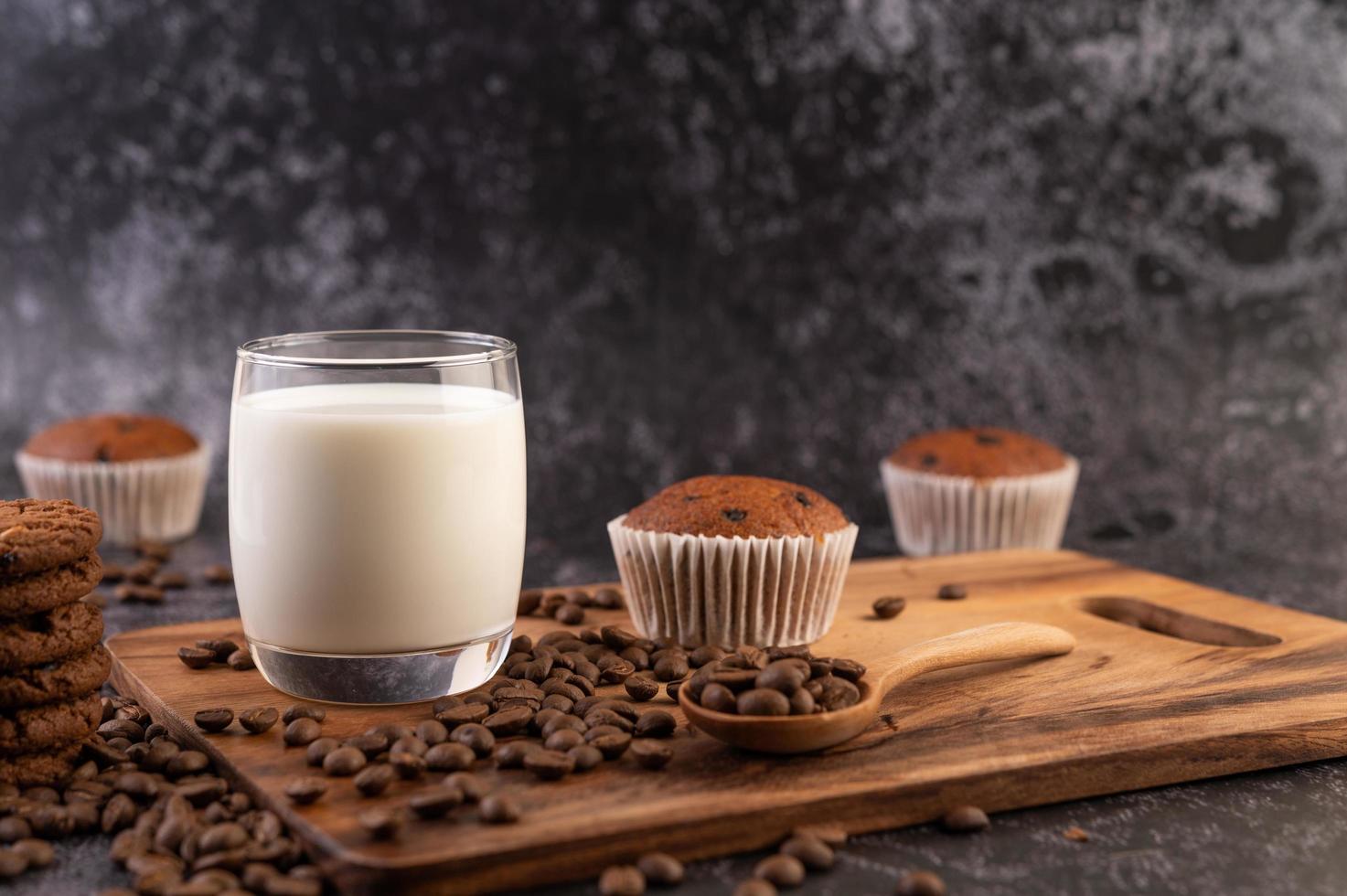 leche en un vaso con granos de café y muffins foto