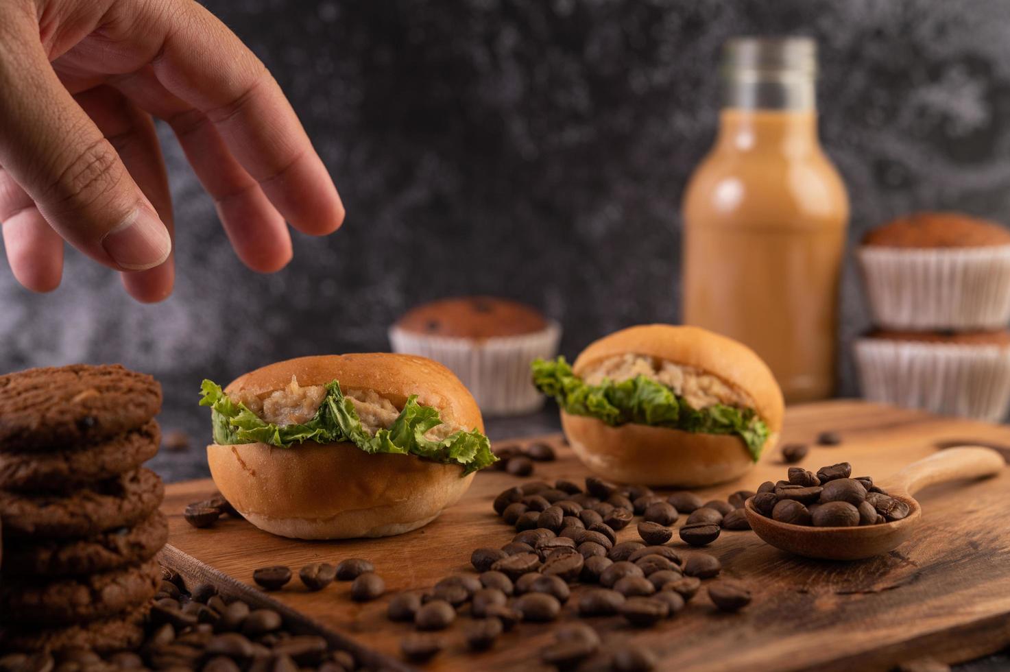 Hamburguesas en una tabla de cortar, incluidos cupcakes y granos de café. foto