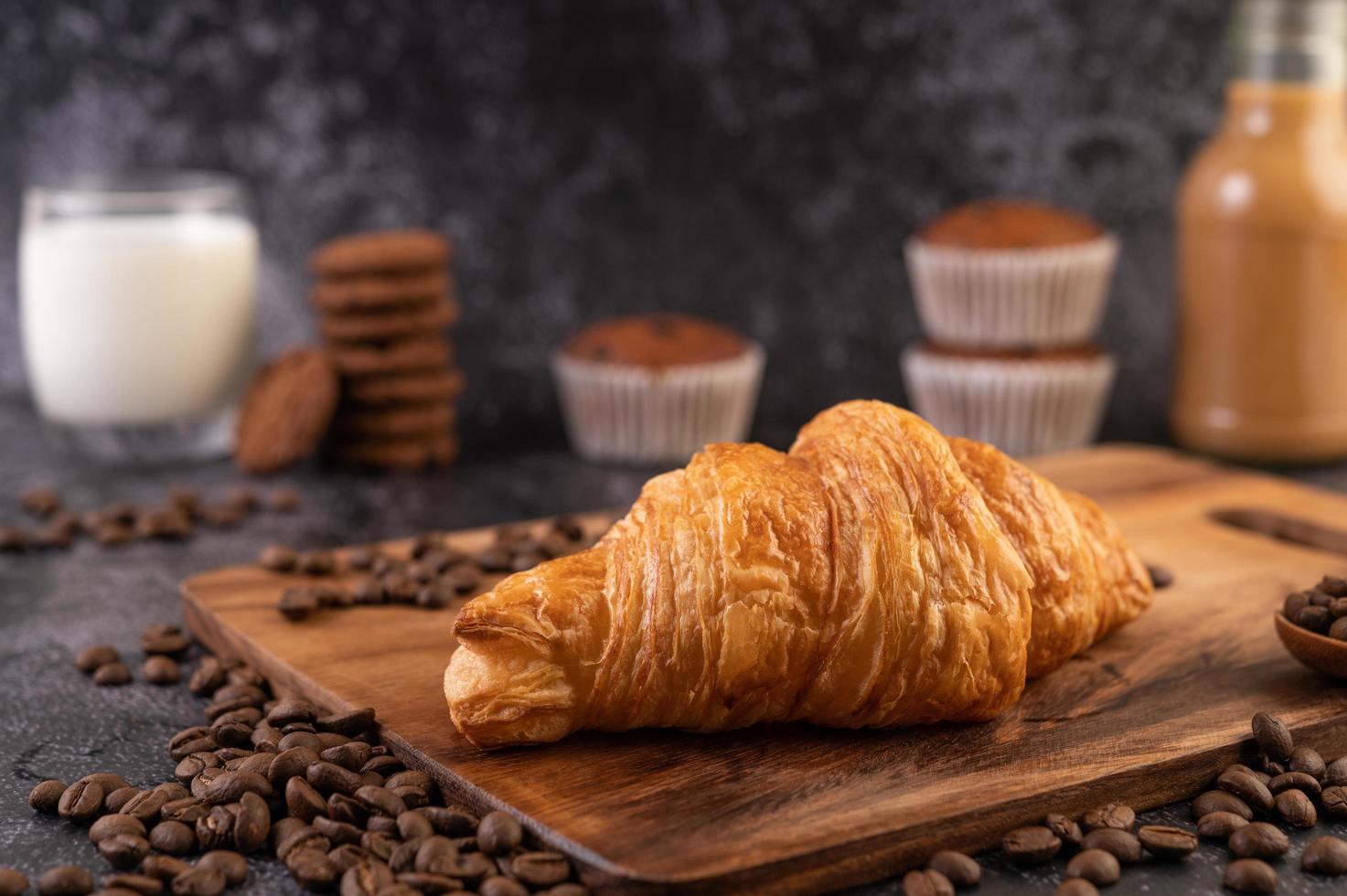 croissant en una tabla de madera con granos de café o. foto