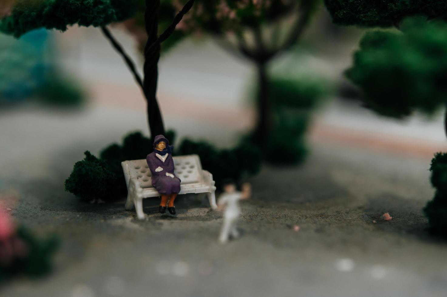 Close-up of miniature people sitting in chairs in the park photo