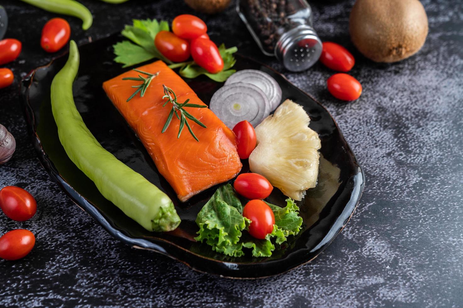 Raw salmon fillet with pepper, kiwi, pineapples, and rosemary photo