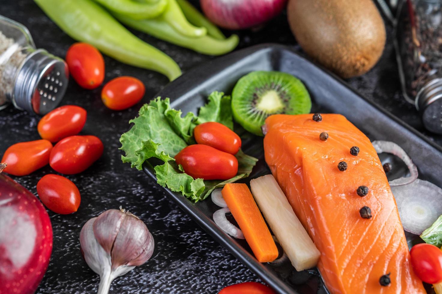 Raw salmon fillet with pepper, kiwi, pineapples, and rosemary photo