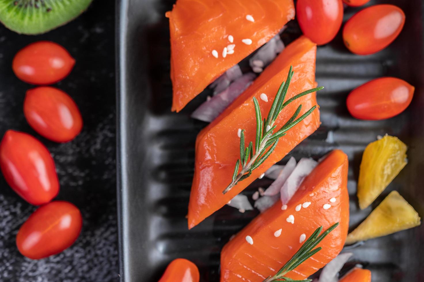 Raw salmon fillet with pepper, kiwi, pineapples, and rosemary photo