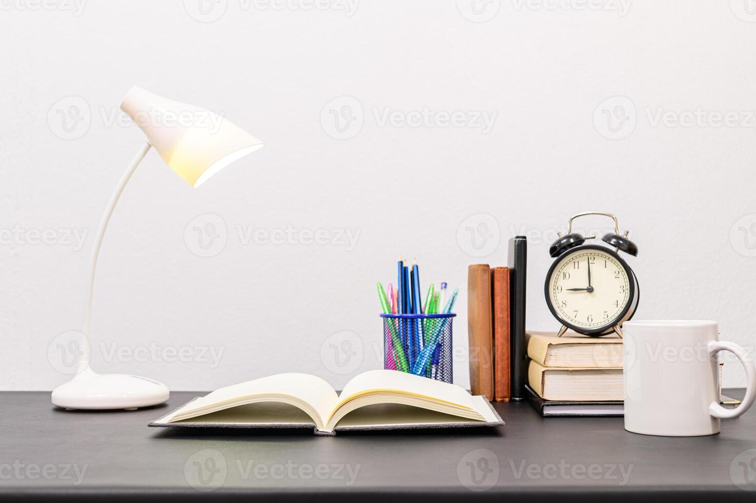 A desk with a lamp, coffee mug, book and alarm clock photo