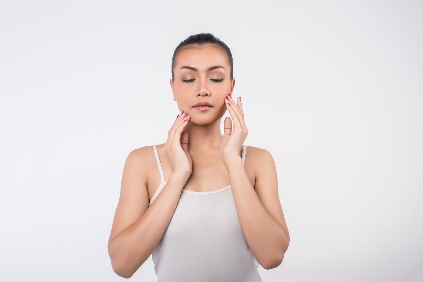 Young woman touching her cheeks on white background photo