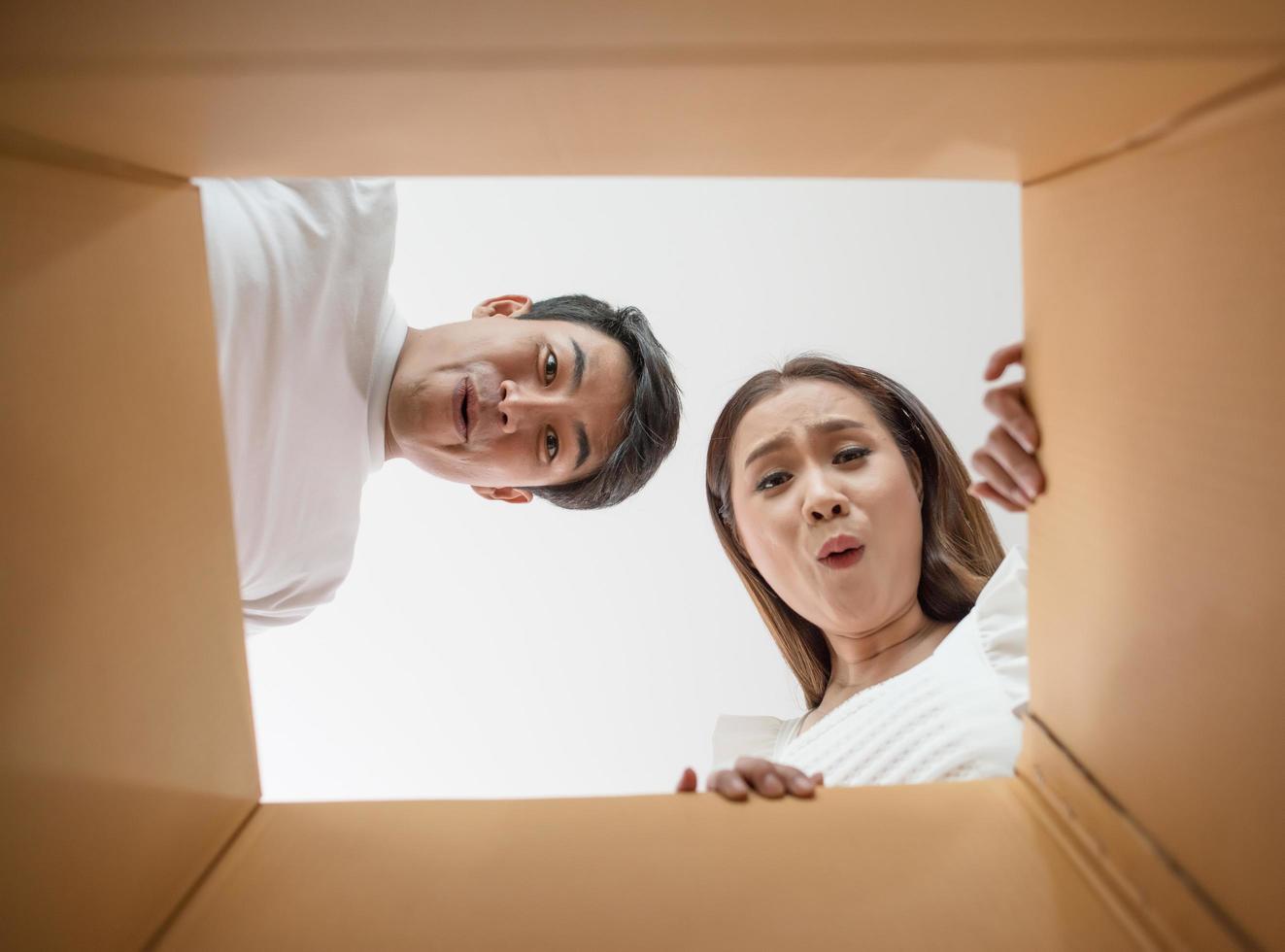Happy couple opening a box and looking inside photo
