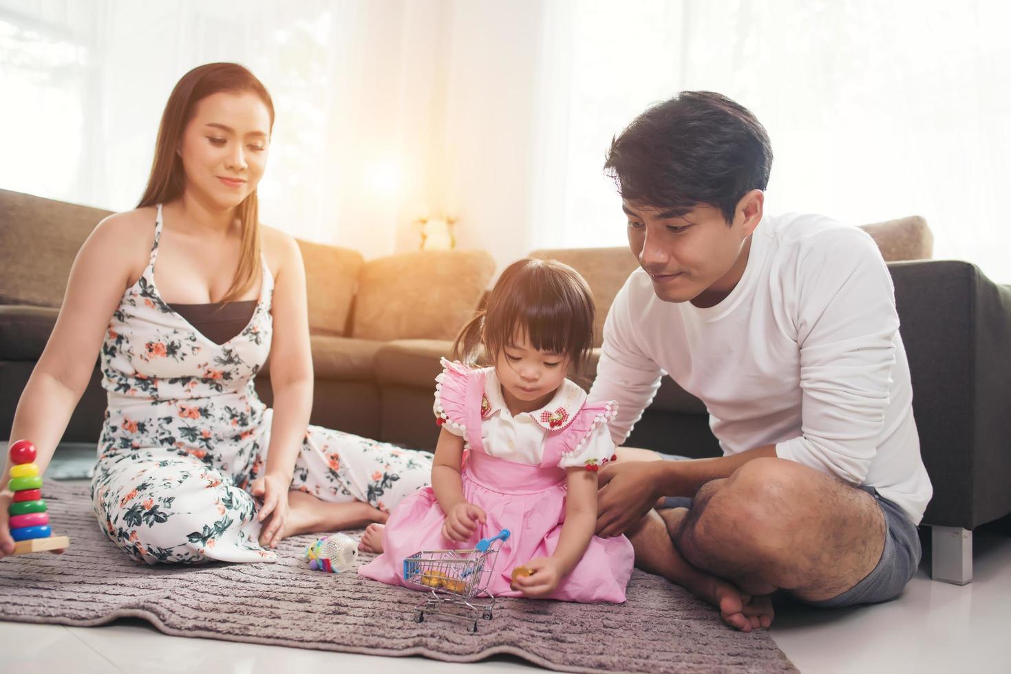 niño con sus padres jugando en el suelo en casa foto