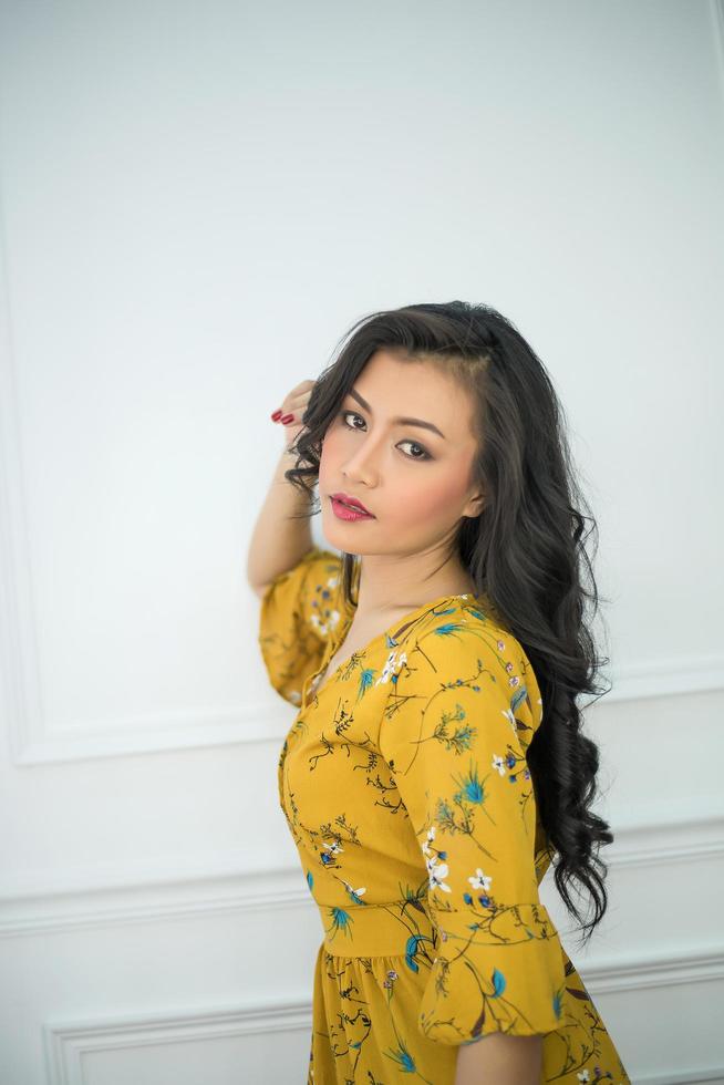 Young woman wearing a yellow dress looks at camera photo