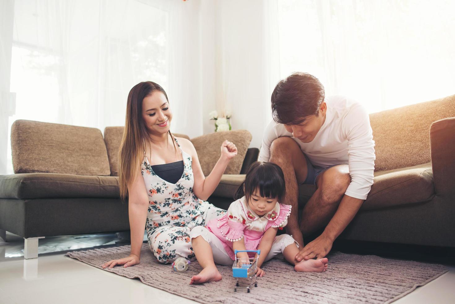 niño con sus padres jugando en el suelo en casa foto