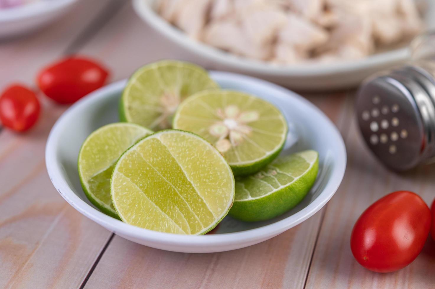 Close-up of a bowl of sliced limes on a wooden table photo