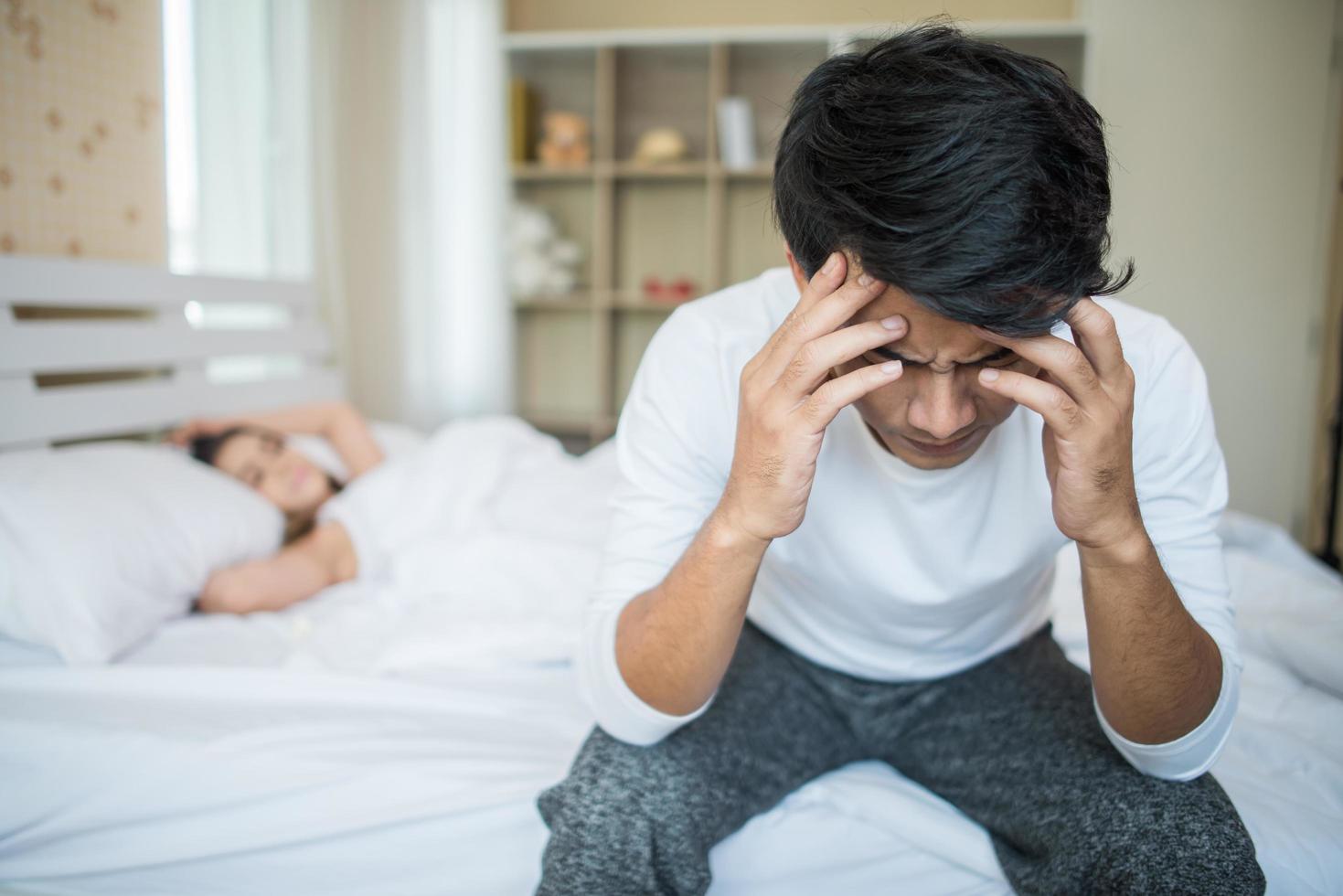 Upset man on the bed after arguing with his girlfriend photo