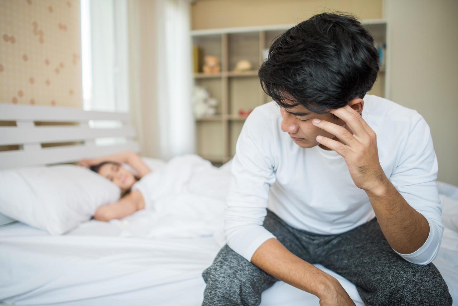 Upset man on the bed after arguing with his girlfriend photo