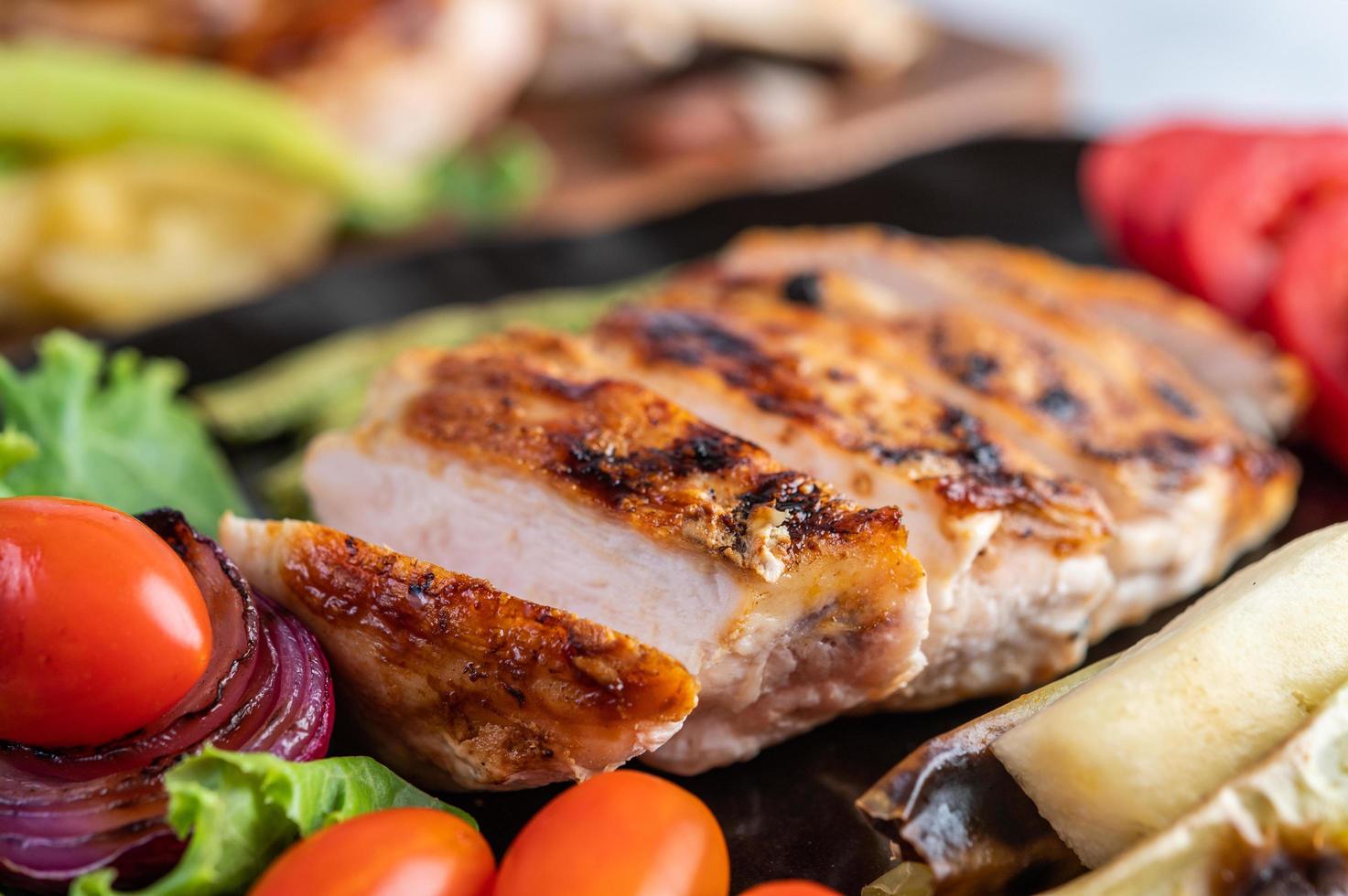 Chicken steak with salad vegetables on a black plate photo