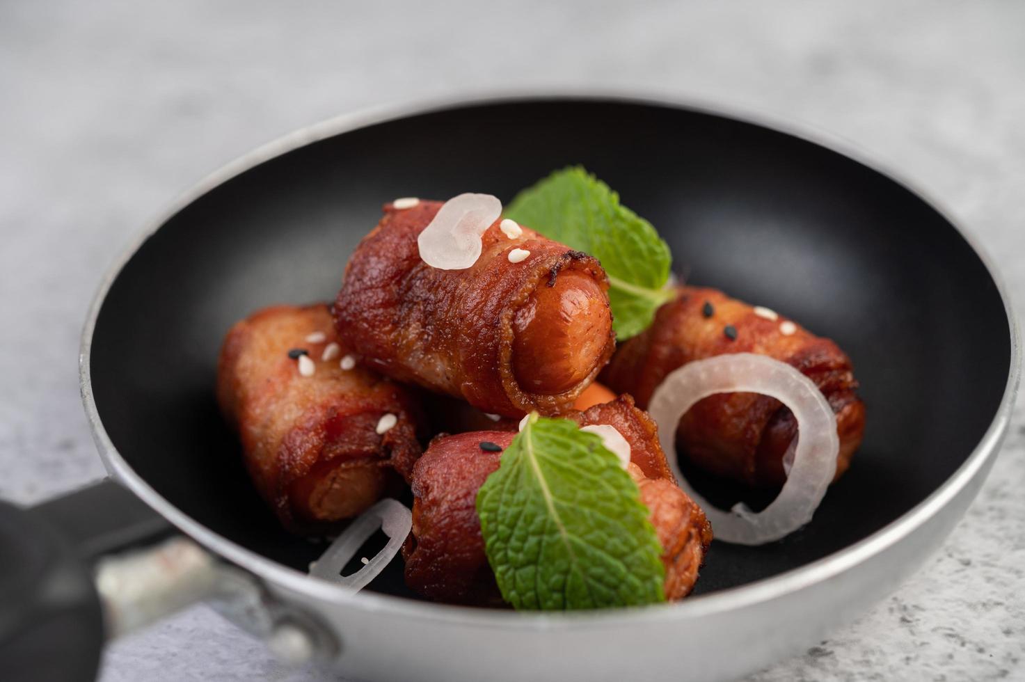 Sausage-wrapped in pork belly in a frying pan photo