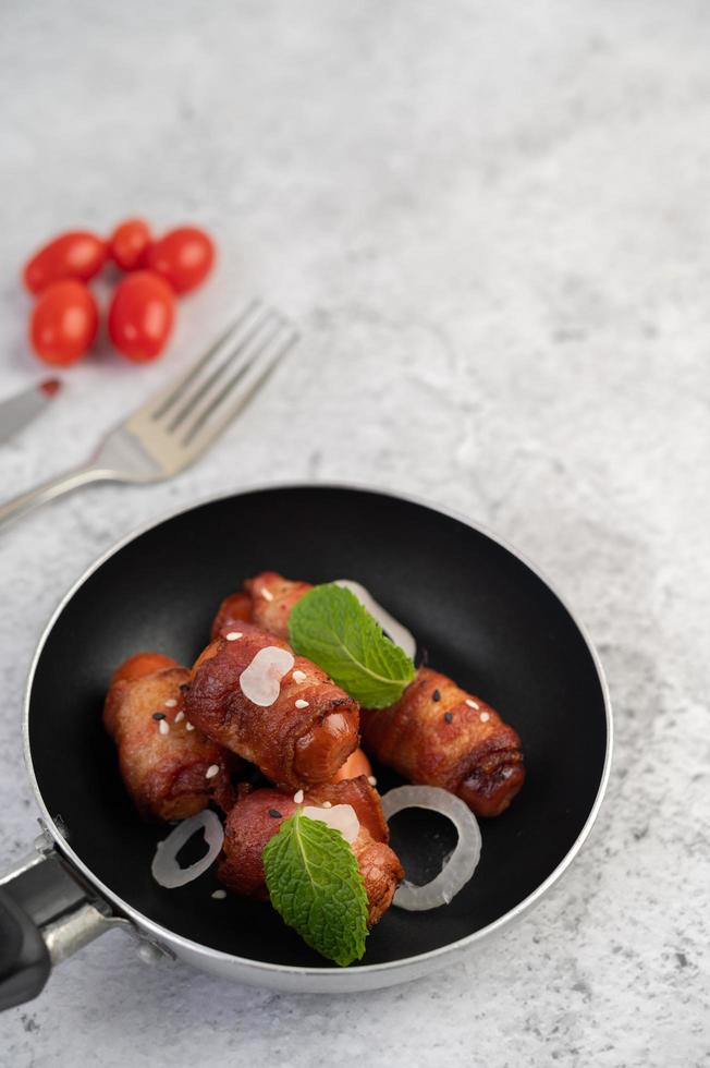 Sausage-wrapped in pork belly in a frying pan. photo