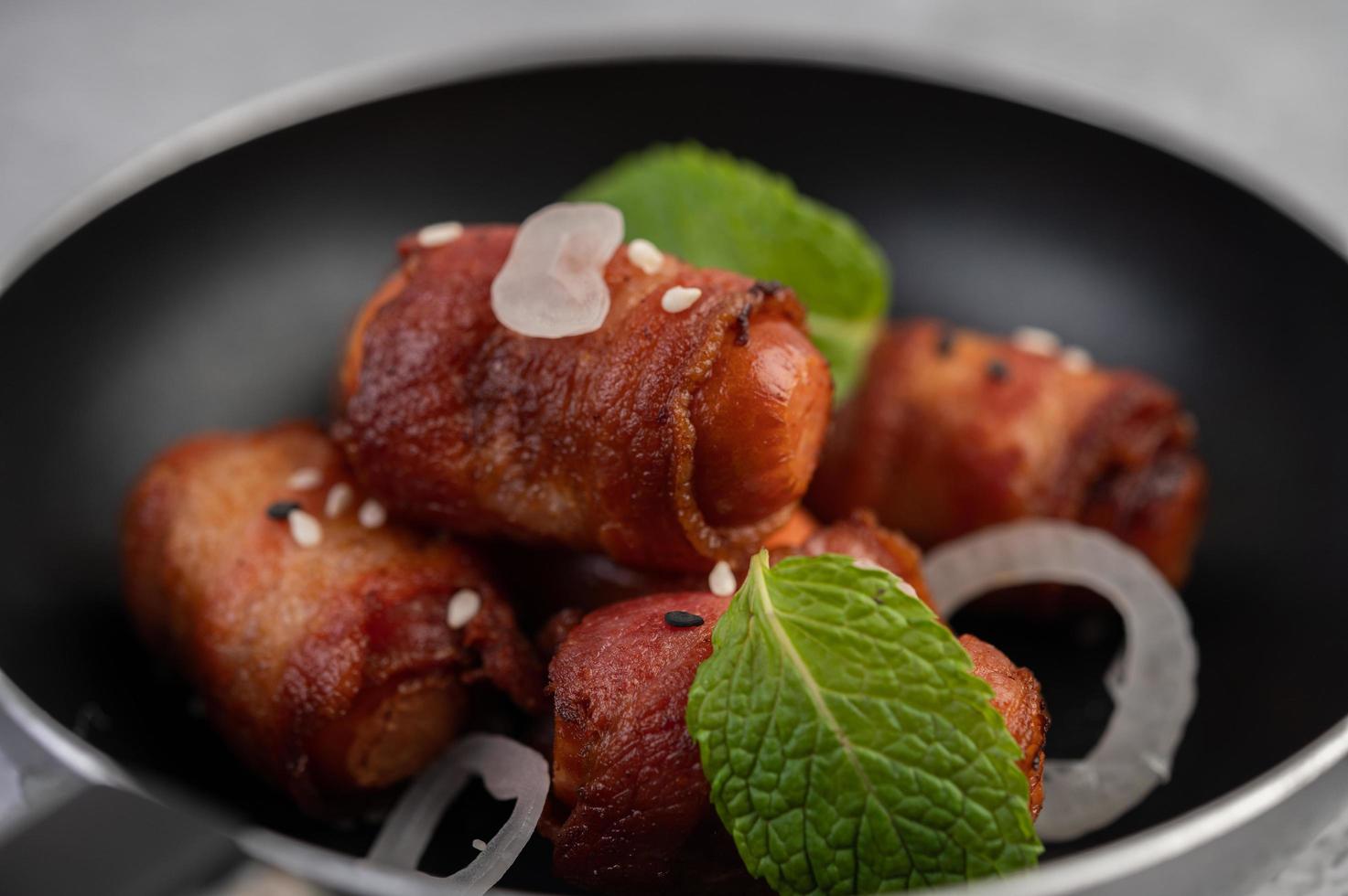 Sausage-wrapped in pork belly in a frying pan photo