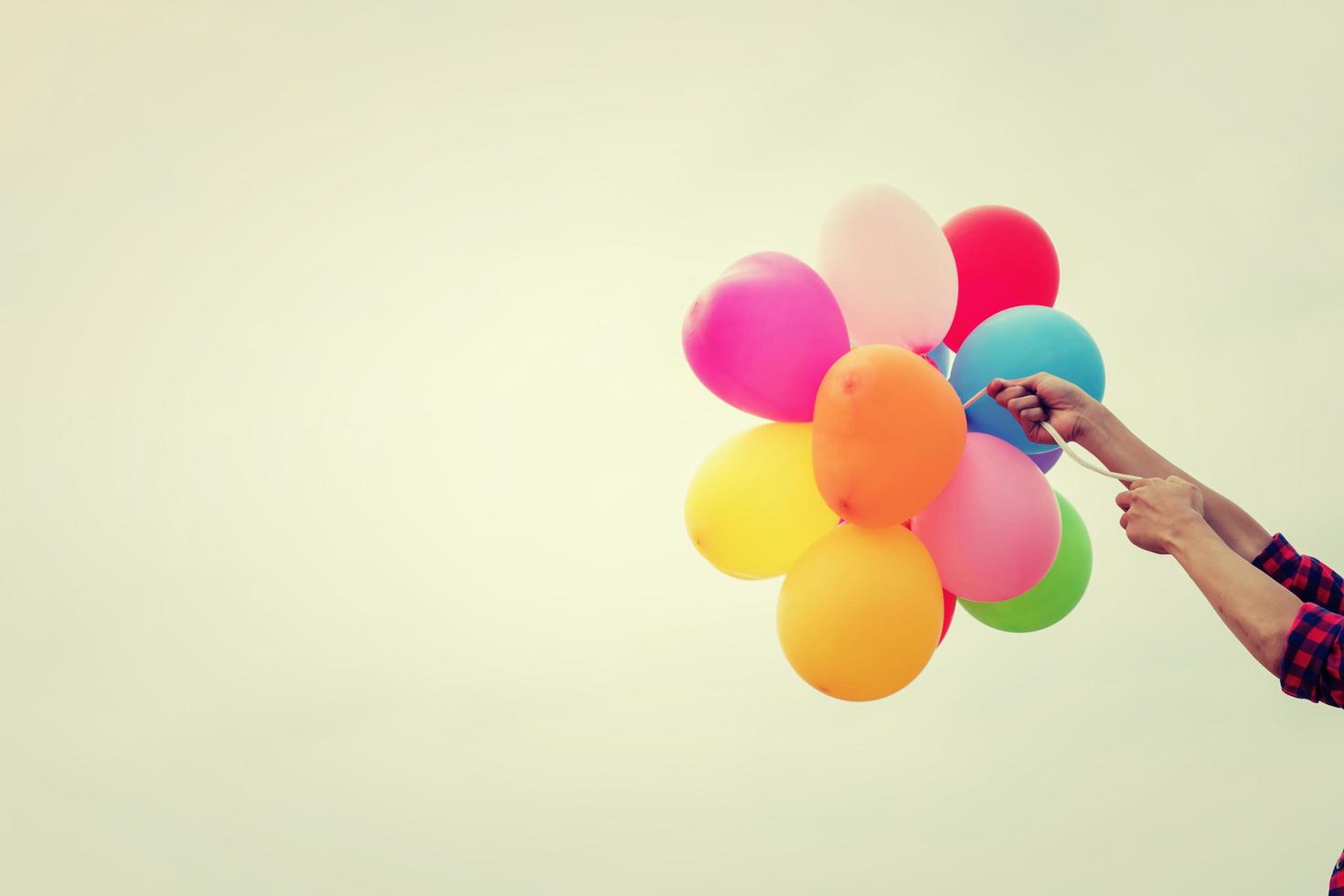Hands holding colorful balloons in the sunshine of summer photo