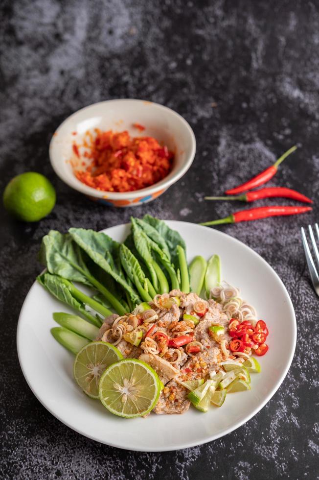 Ensalada picante de cerdo con lima y verduras y acompañamientos foto