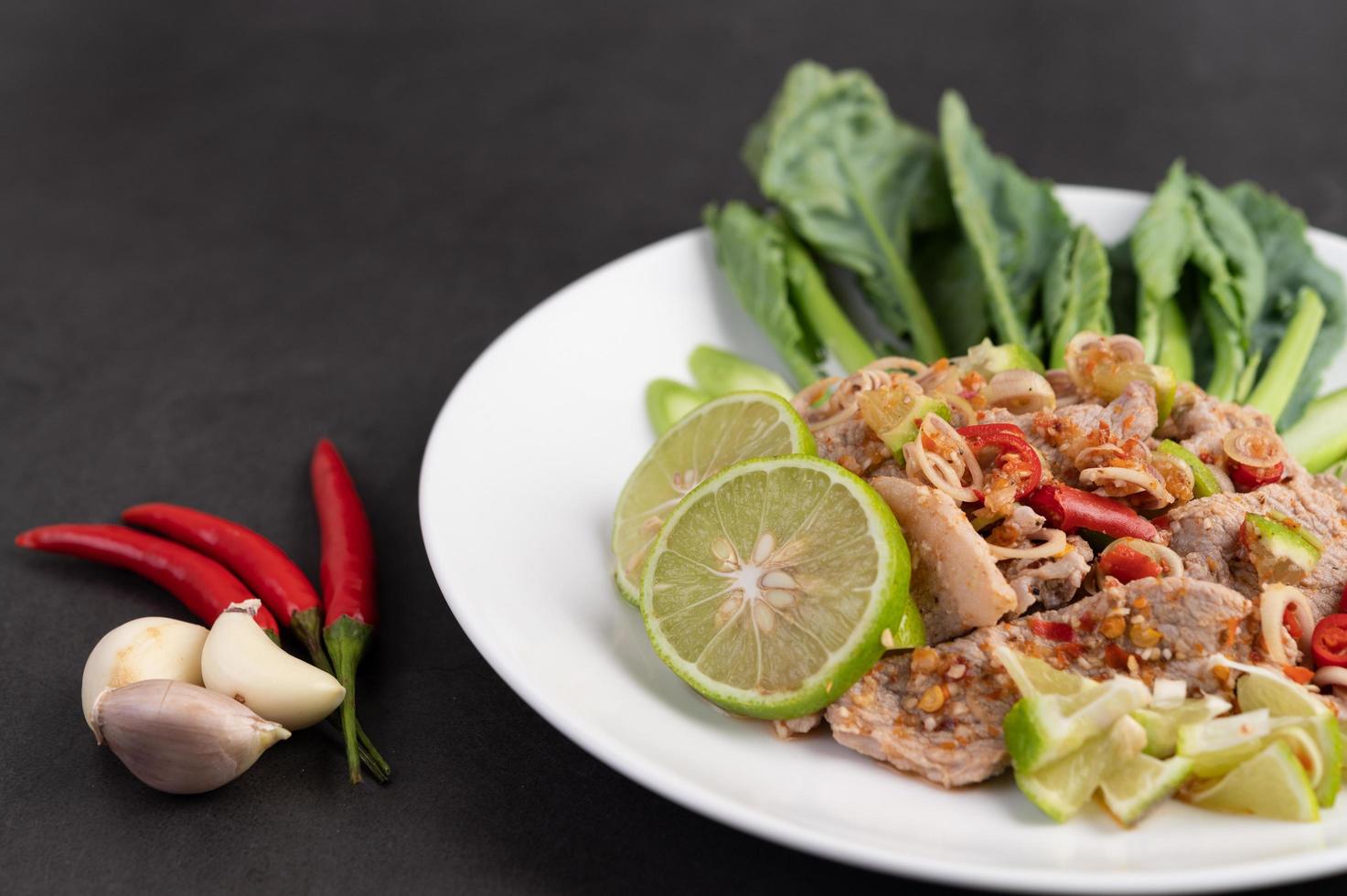 Ensalada picante de cerdo con lima sobre una cama de verduras foto