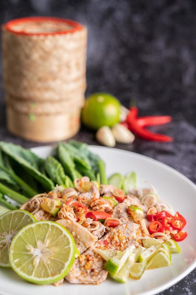 Ensalada picante de cerdo con lima y verduras y acompañamientos foto