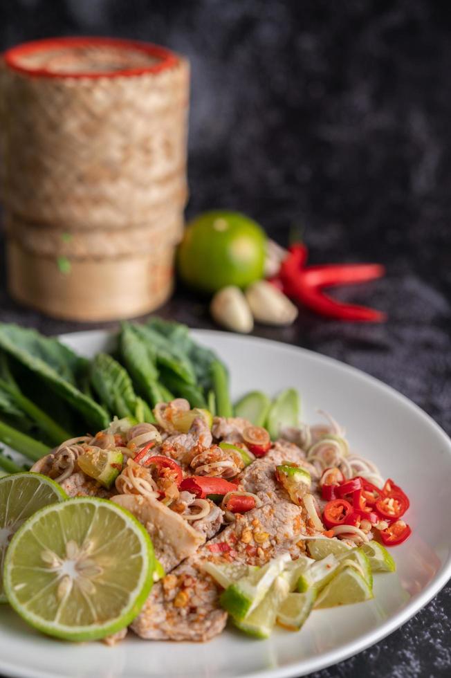 Ensalada picante de cerdo con lima y verduras y acompañamientos foto