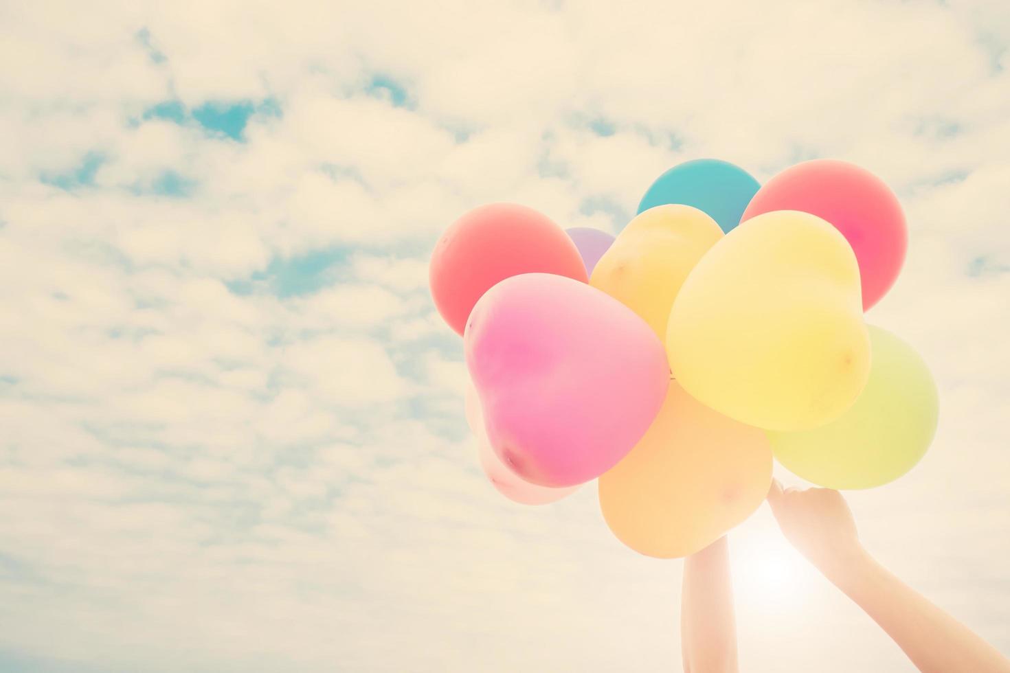 Hands holding colorful balloons in the sunshine of summer photo