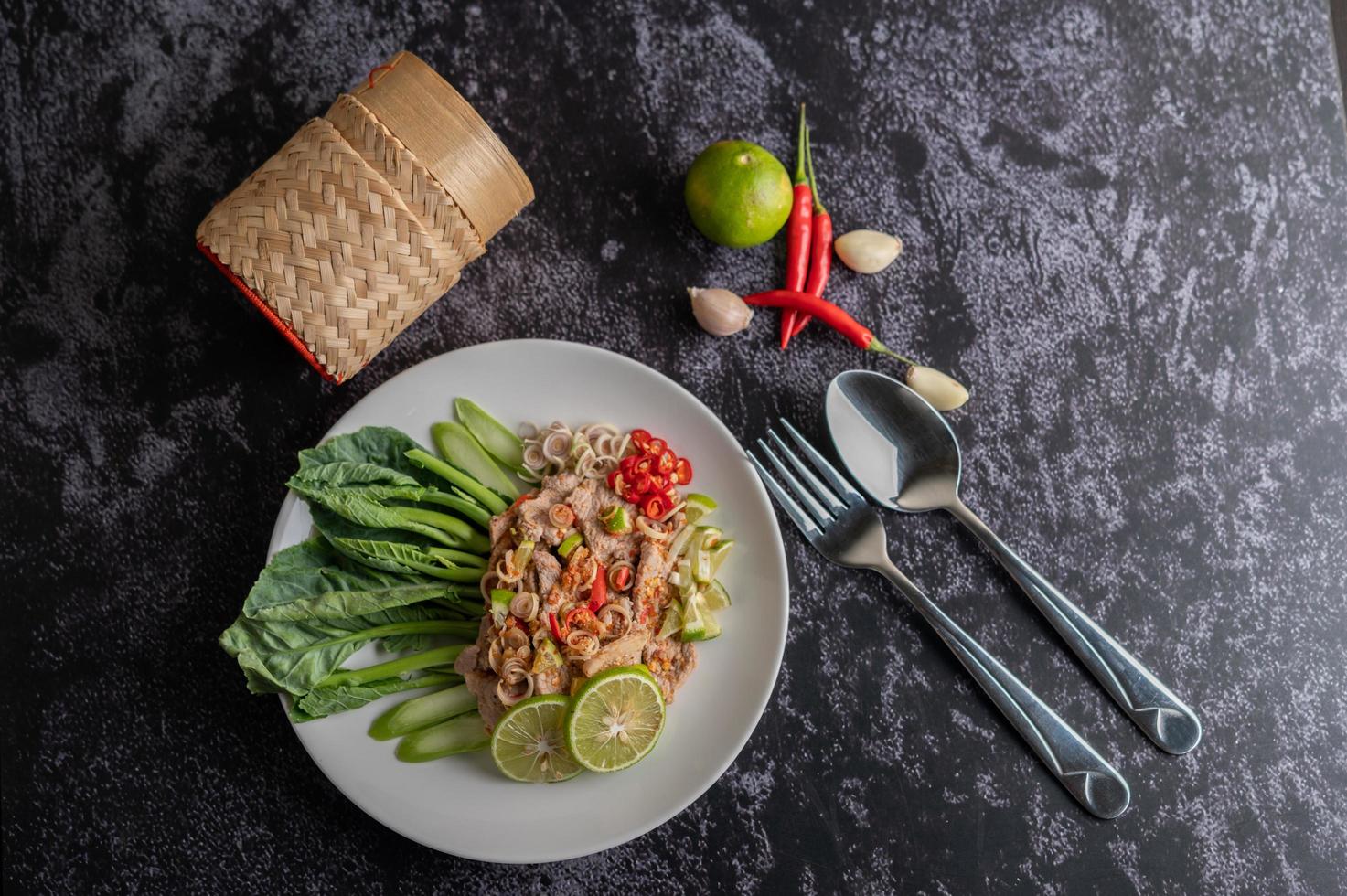 Spicy lime pork salad with greens and sides photo