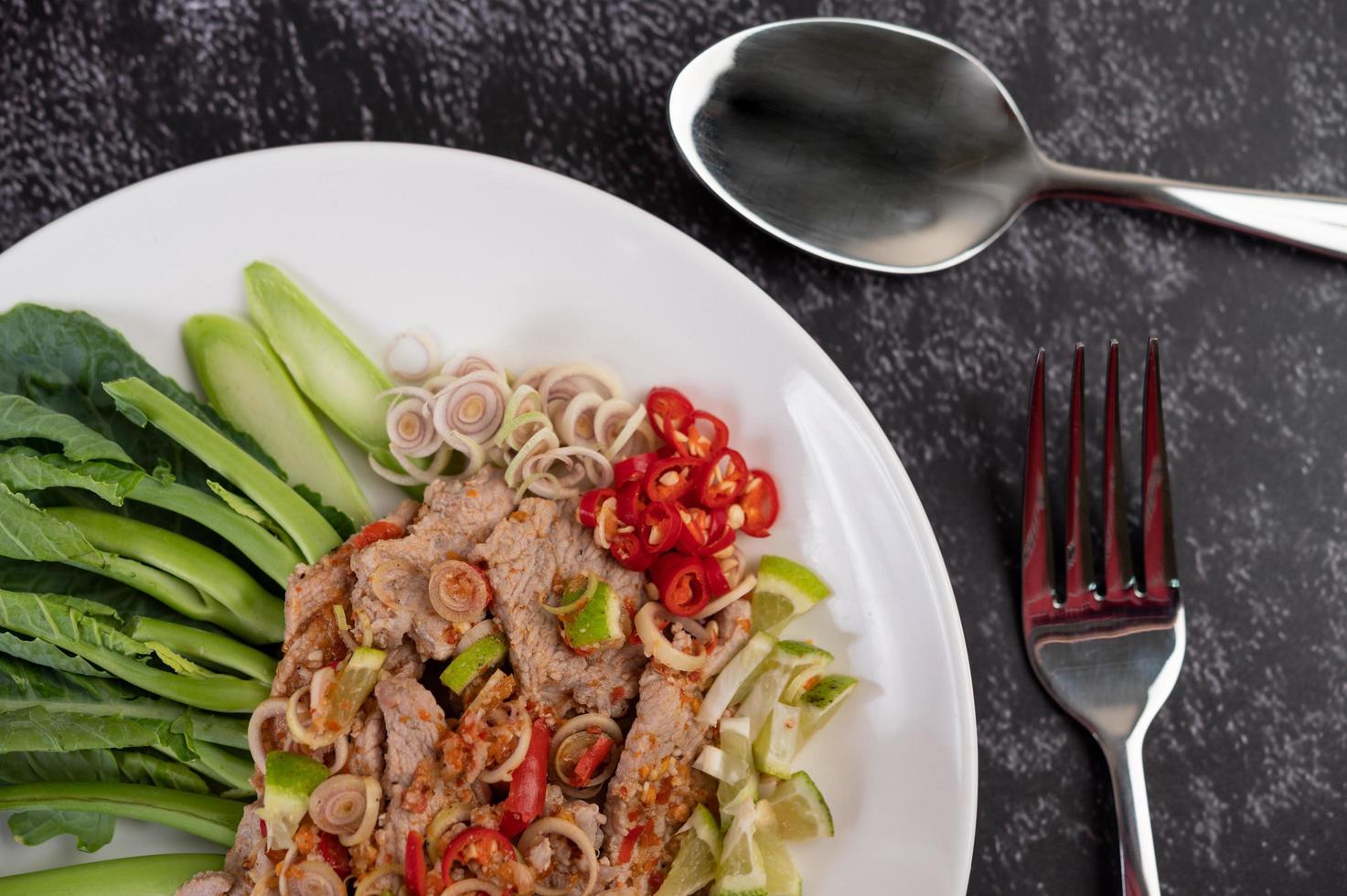 Spicy lime pork salad with greens and sides photo