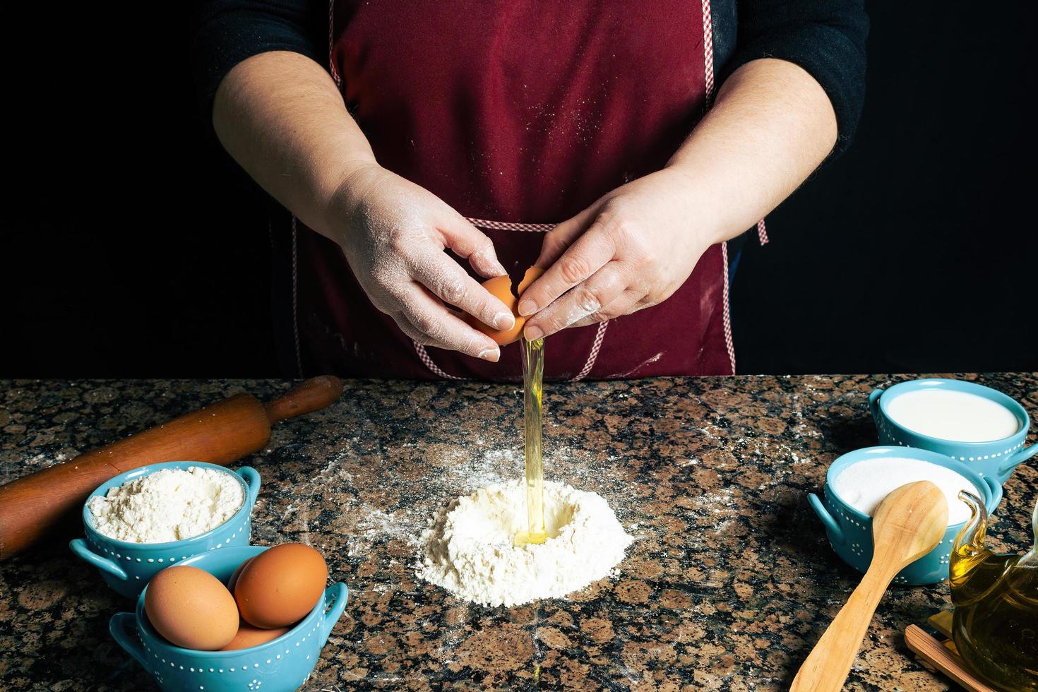 Person breaking eggs into flour photo