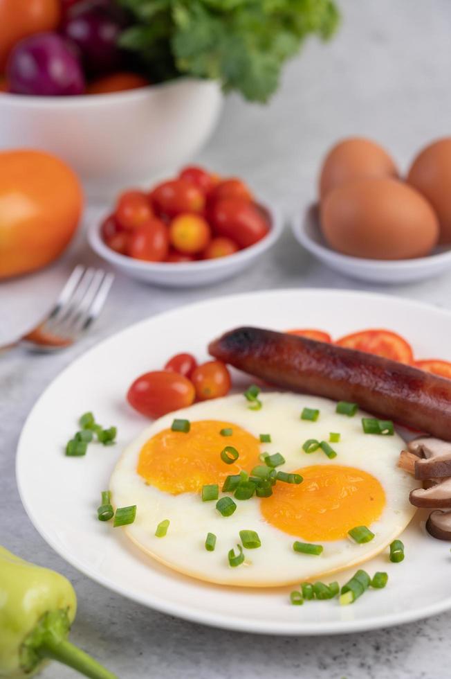 Breakfast plate with fried eggs, tomatoes, Chinese sausage and mushrooms photo