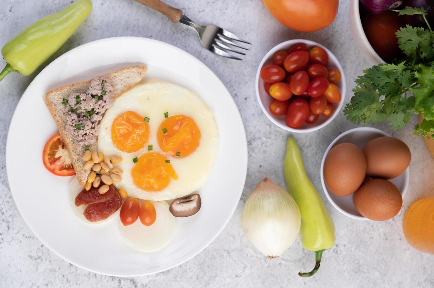 Fried eggs, sausage, minced pork, bread and red beans photo