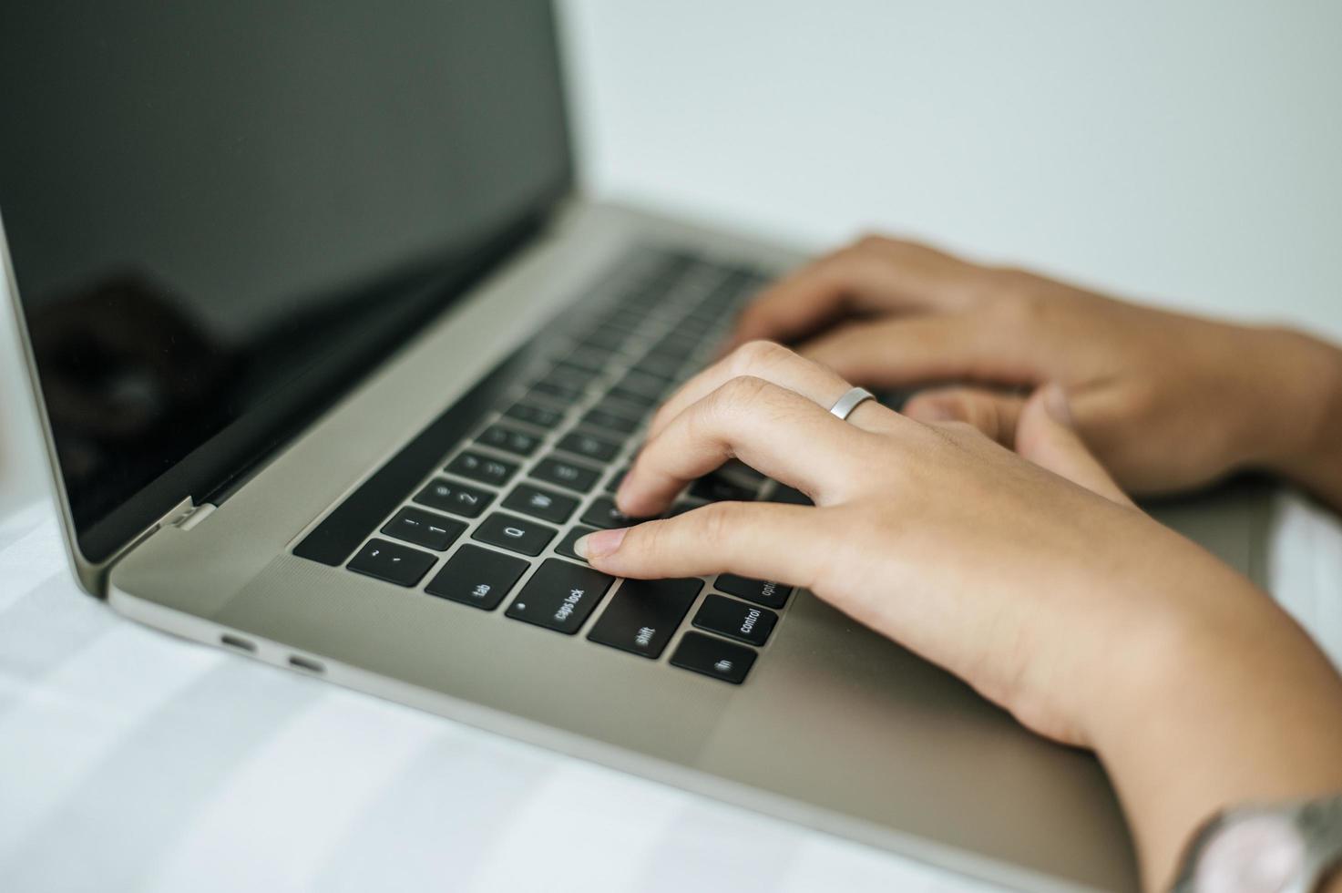 manos de mujer escribiendo en la computadora portátil foto