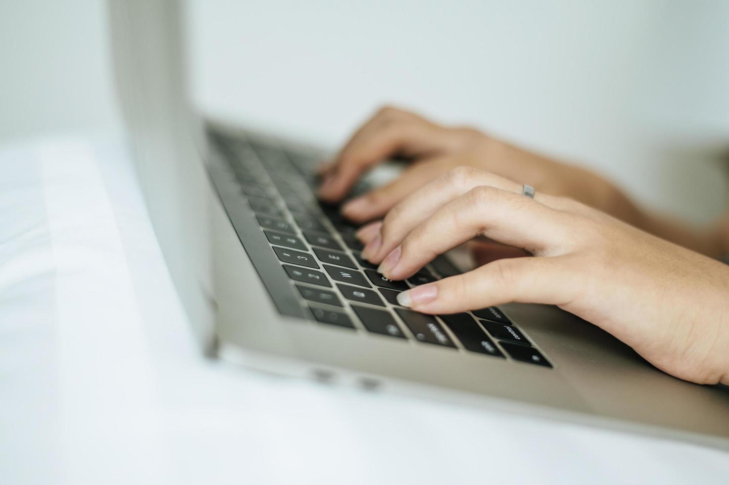 manos de mujer escribiendo en la computadora portátil foto