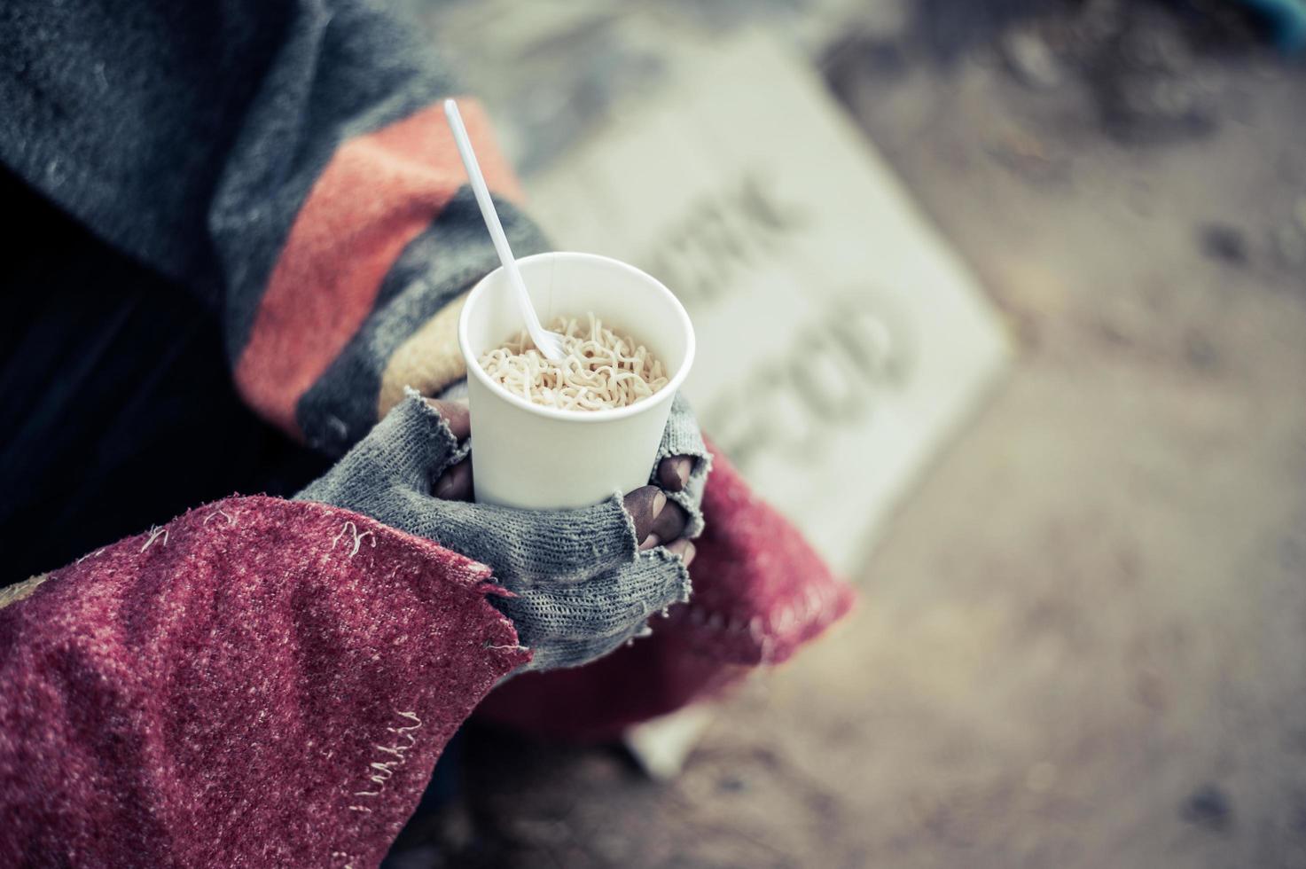 Person sits wrapped in cloth and eating noodles photo