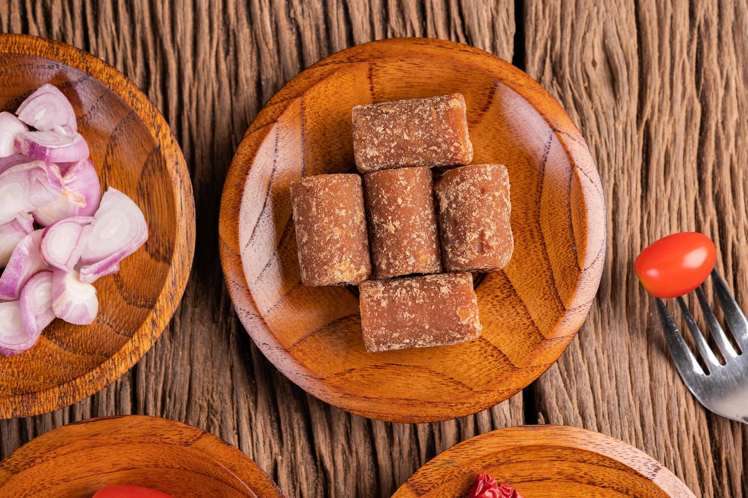 Palm sugar and red onions on a wooden plate photo