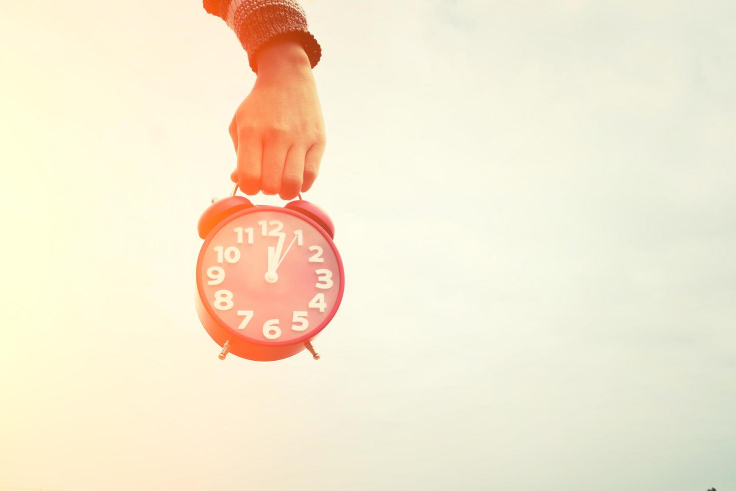 Hand holding a red alarm clock photo