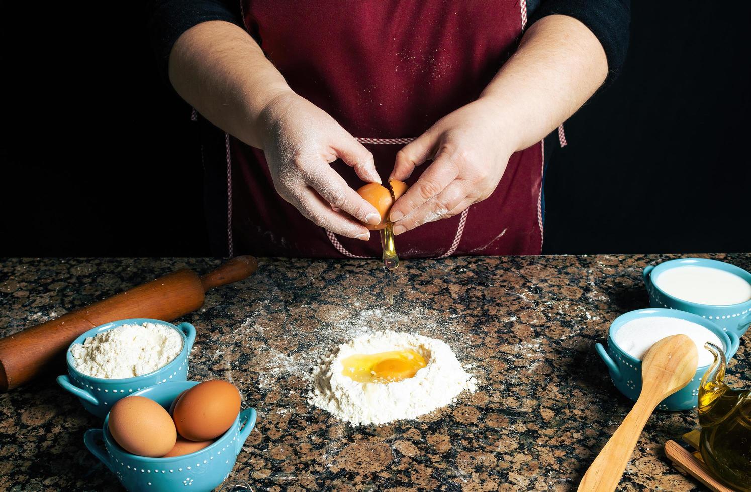 Person cracking eggs in flour photo