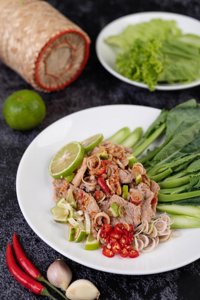 Ensalada picante de cerdo con lima sobre una cama de verduras foto