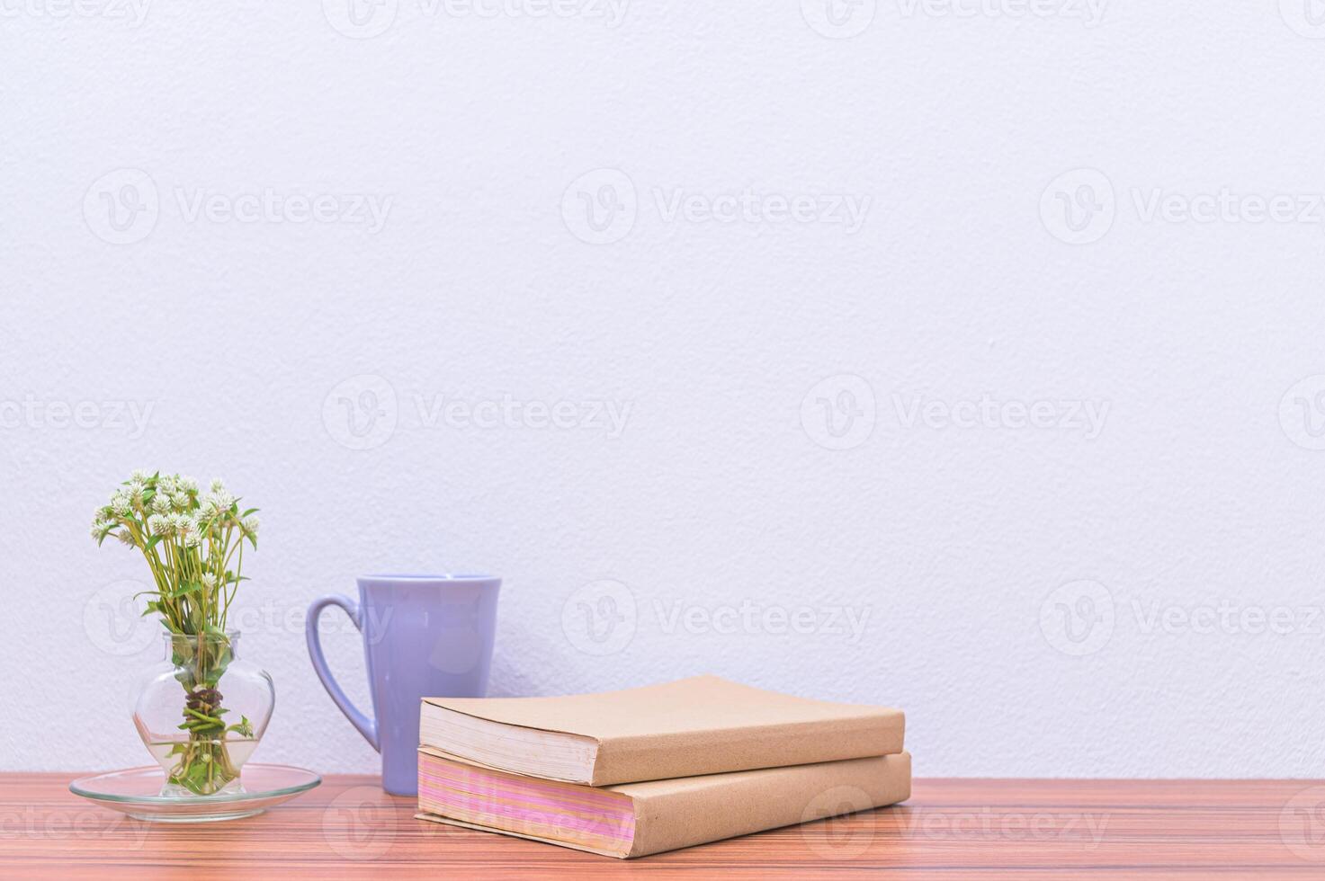 A vase with a plant and a book on a table photo