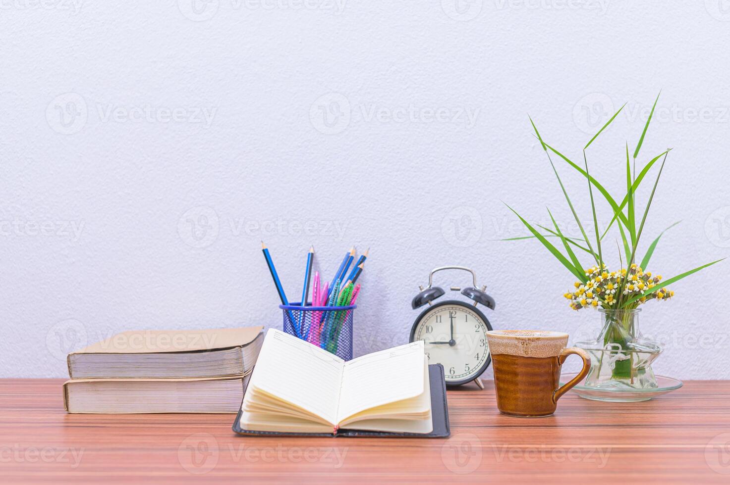 A book, coffee cup, and vase of flowers sit on a table photo
