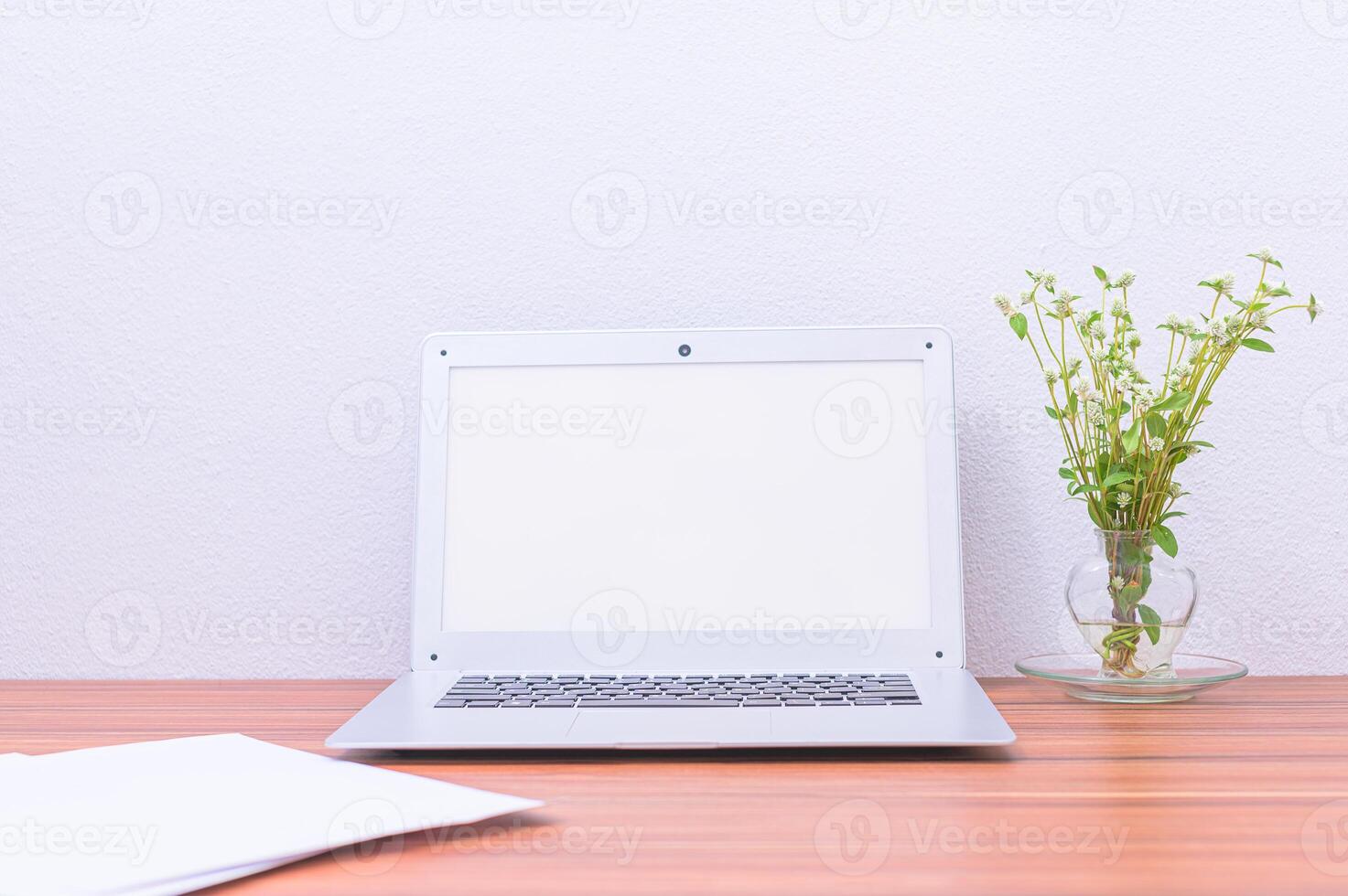 Laptop on wooden desk with blank white screen photo