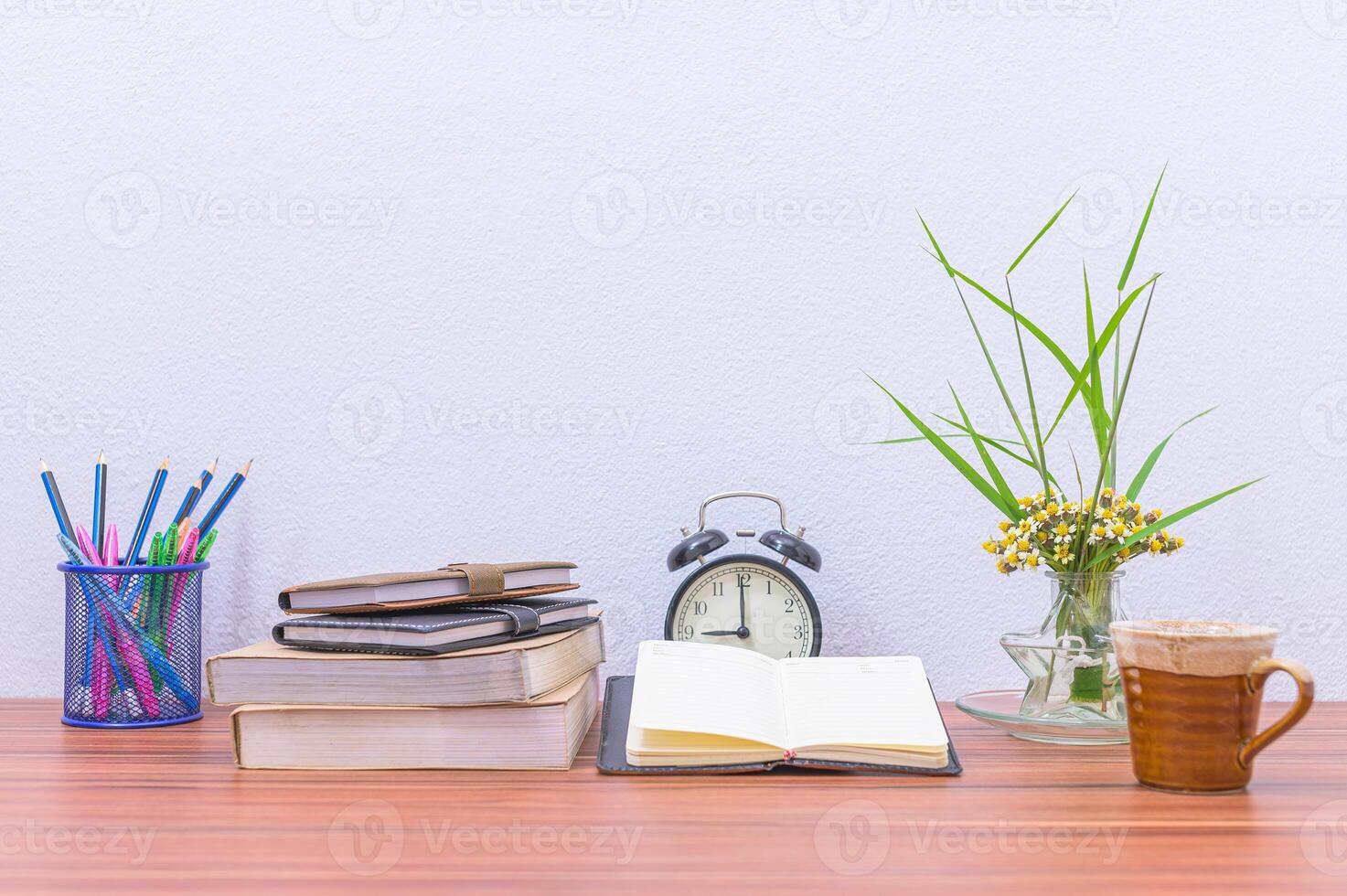 A desk with books, coffee cup, and an alarm clock photo