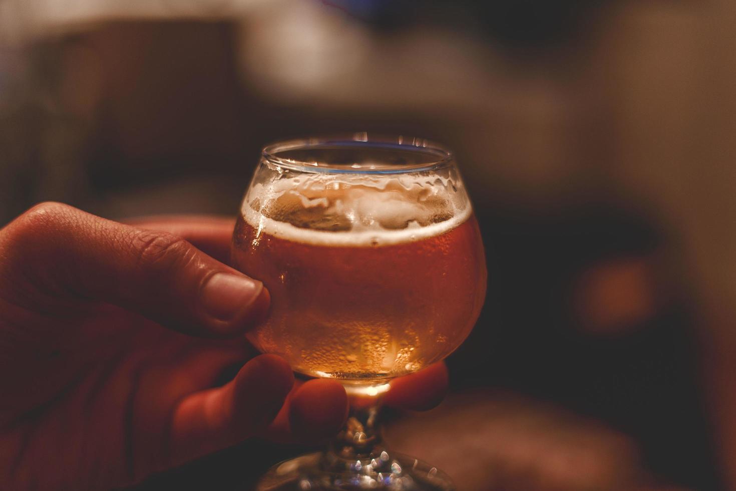 persona sosteniendo un vaso de cerveza foto