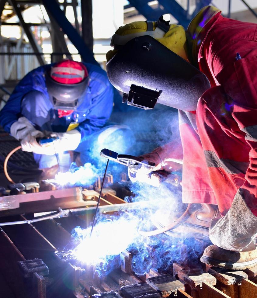 dos soldadores ensamblando la pieza de trabajo foto