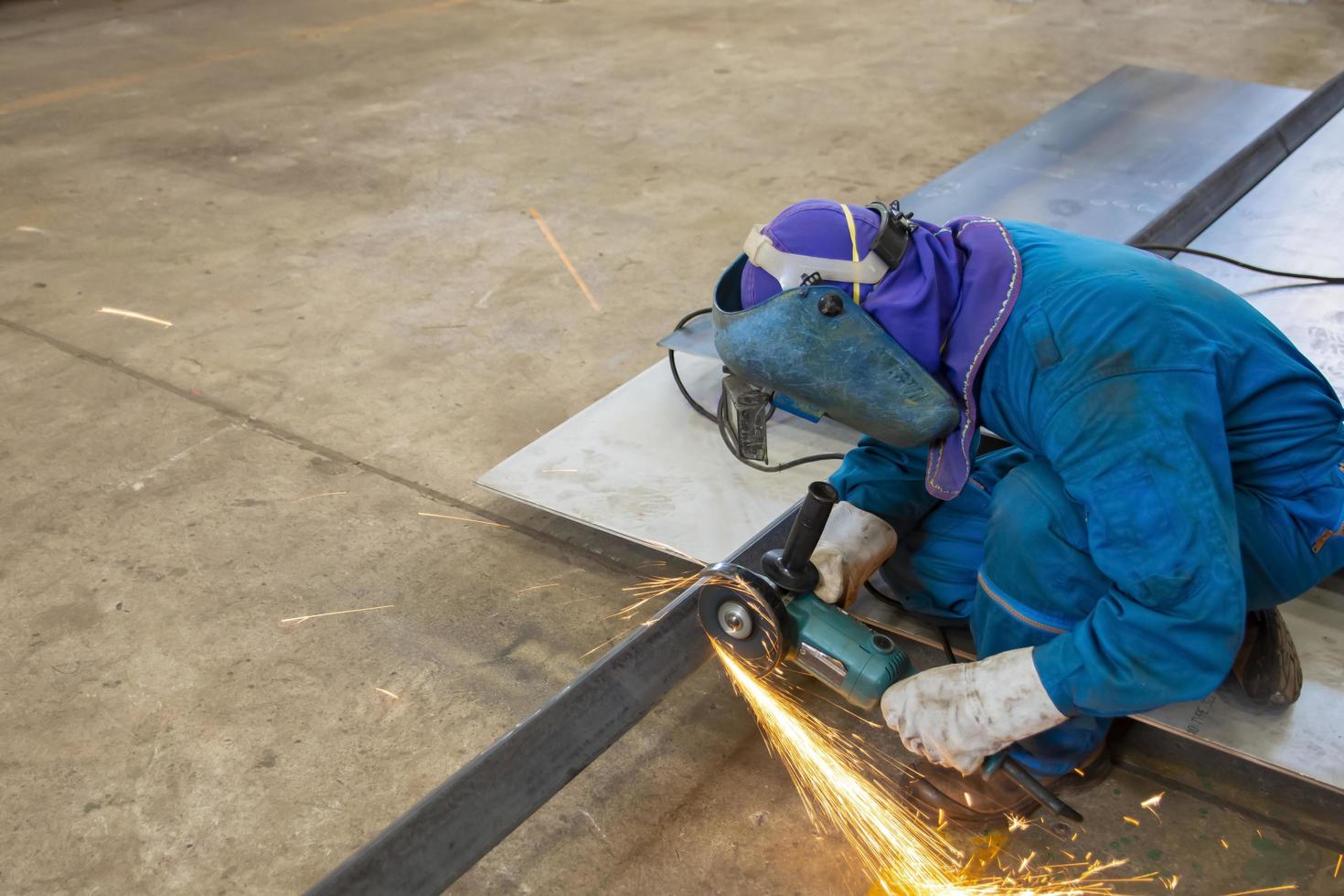 Trabajador en uniforme azul cortando hojas de metal foto