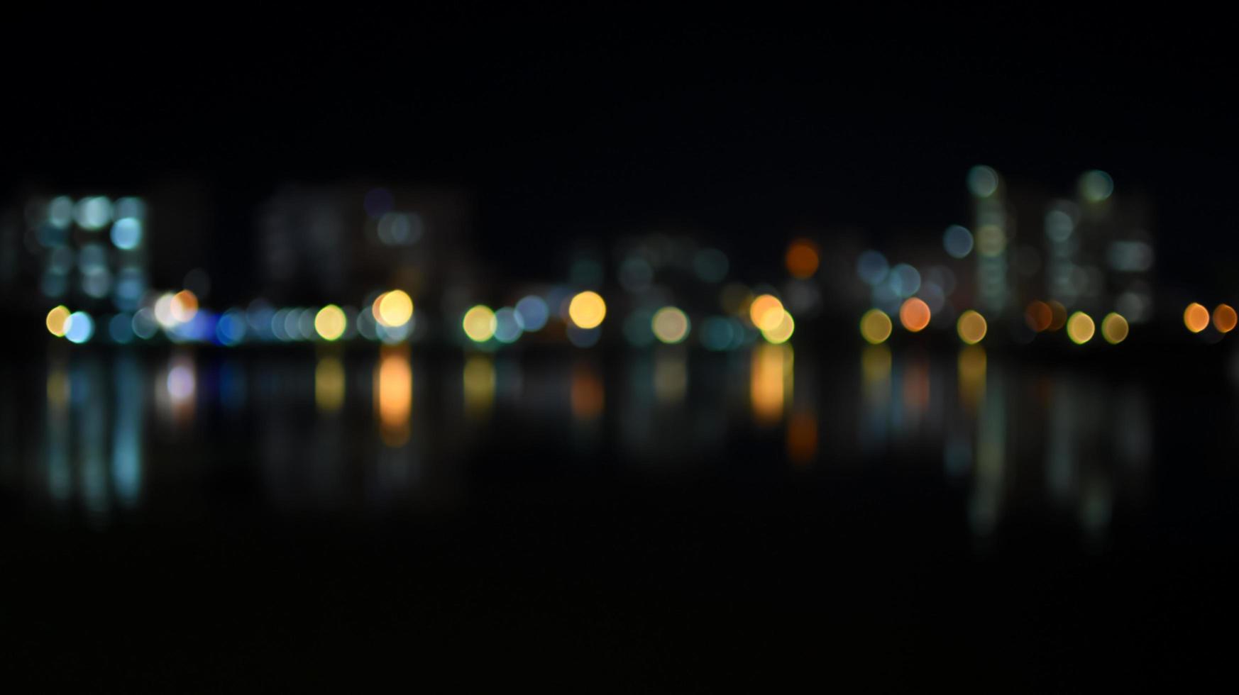 Bokeh colorido del horizonte de la ciudad desde el río en la noche foto