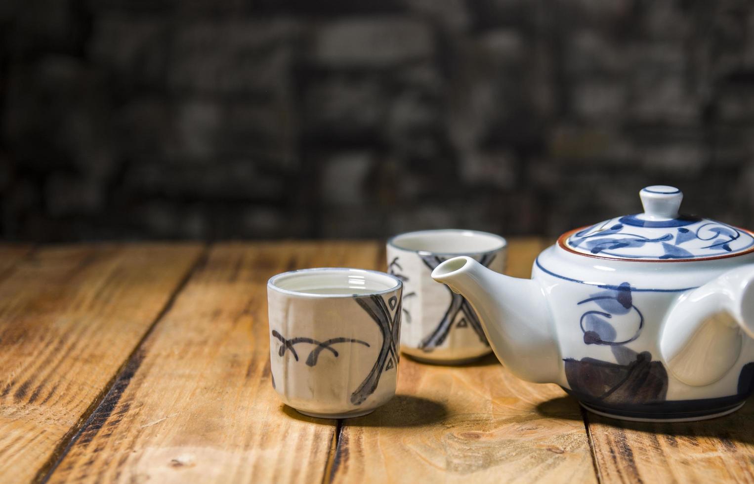 Teapot and two teacups on the old wooden table photo