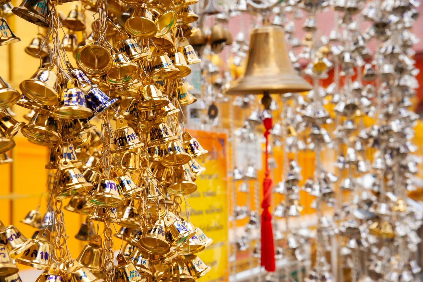 pequeñas campanas de oro colgando en el templo tailandés foto